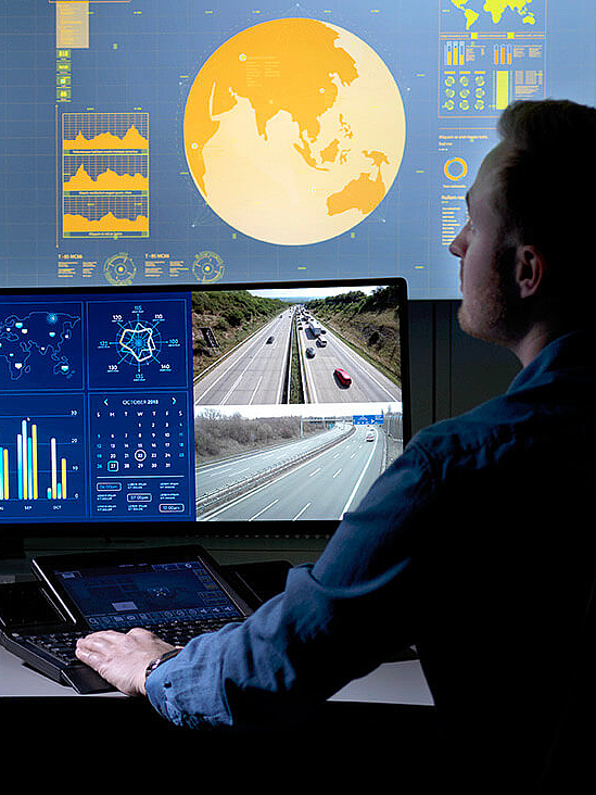 Woman sitting in control room in front of several screens and a video wall