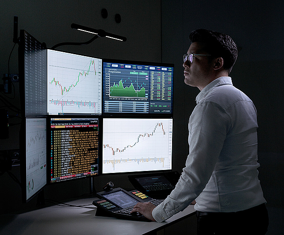 Man standing at trading workplace in front of multiple screens