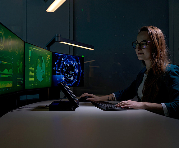 Woman in control room in front of several screens