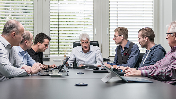 Team aus mehreren Personen an einem großen Konferenztisch im Gespräch