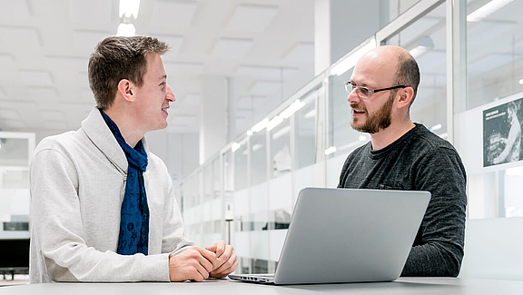 Zwei Männer an einem Laptop im Gespräch