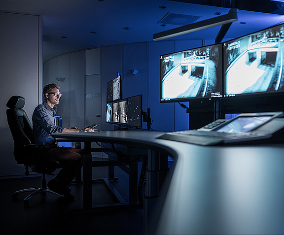 Man in control room in front of screens and video walls