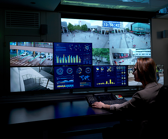 Woman sitting in front of several screens and a large video wall